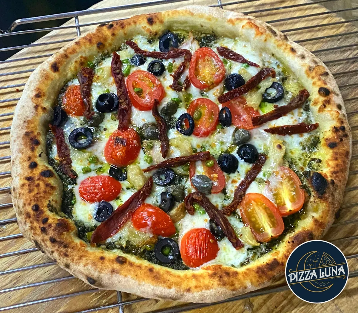 Pizza Luna pesto pizza with tomatoes, olives and sun-dried tomatoes